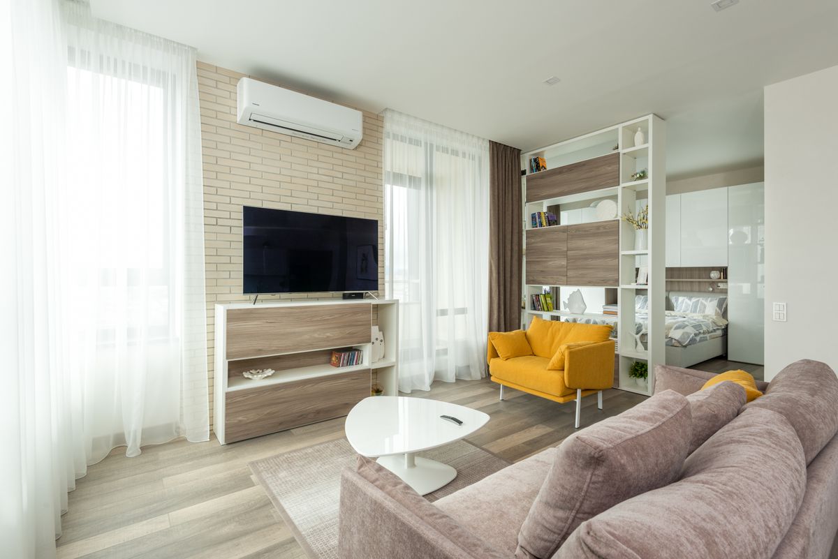 Illustrative bright apartment living room with a sleeping area visible; not a photo of Royal Crest Apartments